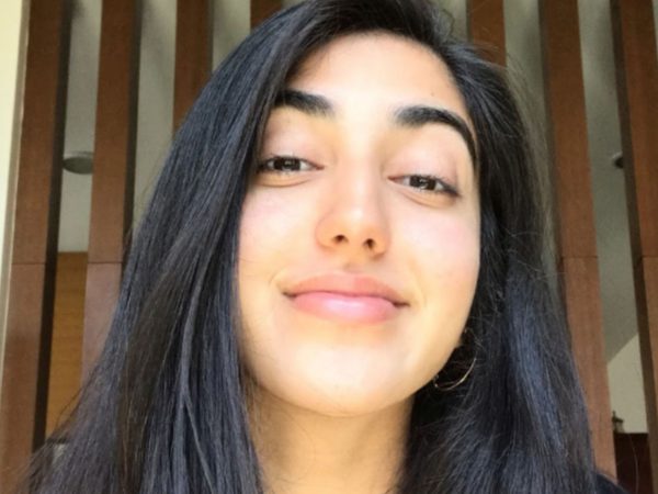 A young woman with long dark hair smiles subtly while looking at the camera