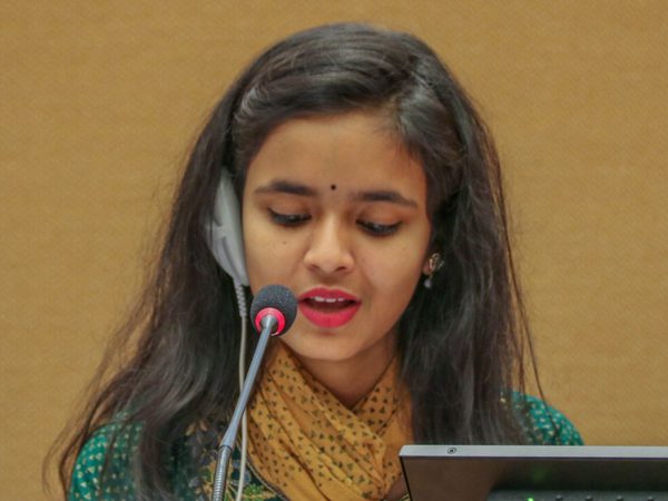 Young woman speaking at a podium with a microphone and earpiece