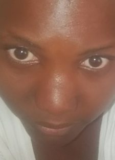 A young woman in a white shirt looks up at the camera with a soft neutral expression