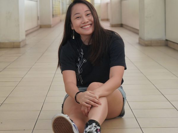 Smiling woman sitting on a tiled corridor floor