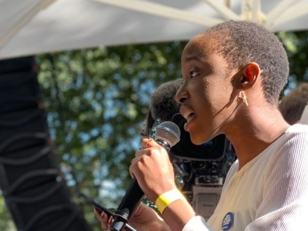 A person speaks passionately into a microphone at an outdoor event