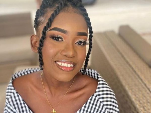 Smiling woman with braided hair and off-shoulder checkered top, sitting in a relaxed setting