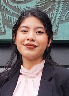 A confident woman with long dark hair smiles subtly