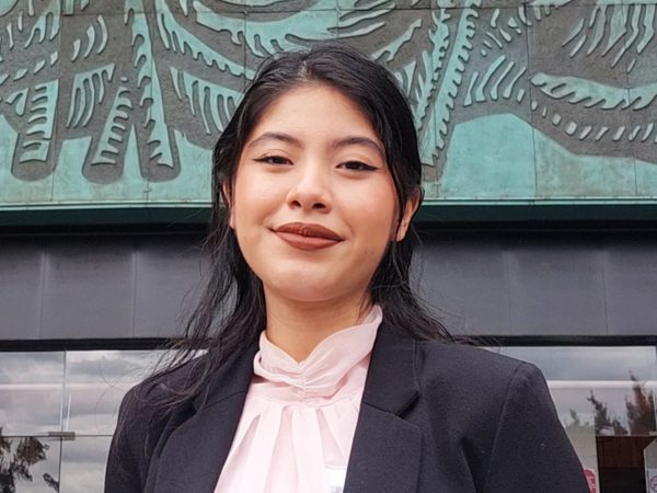 A confident woman with long dark hair smiles subtly