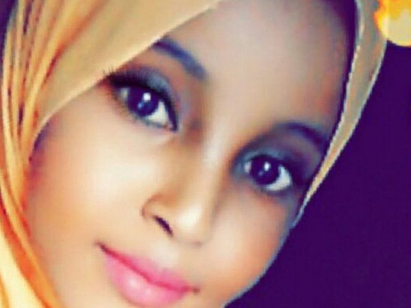 A person wearing a peach-coloured headscarf smiles softly.