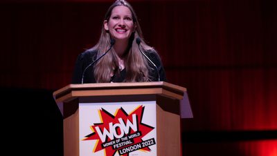The author Laura Bates stands at a lectern at the WOW Festival