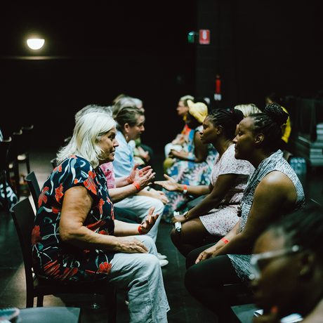 People seated in pairs facing each other in a dimly lit room, engaged in conversation.