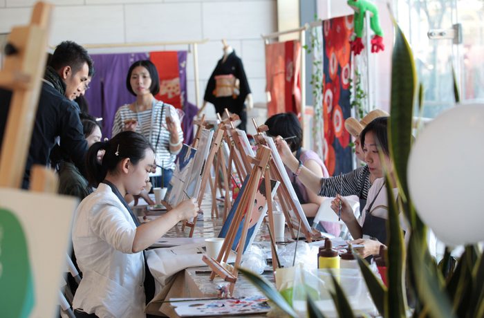 A group of people engaged in painting at easels in a bright, colourful studio with art supplies scattered around.